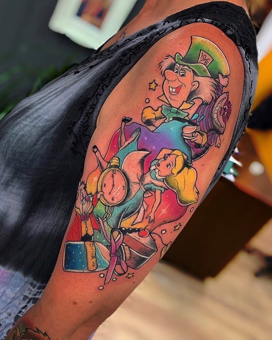 Colorful cartoon tattoo sleeve with Alice in Wonderland characters on an upper arm